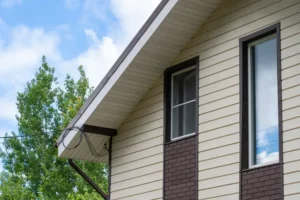 The side of a residential home with with new brown and tan Siding, Soffit & Fascia installed by Prairie State Siding