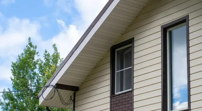 The side of a residential home with with new brown and tan Siding, Soffit & Fascia installed by Prairie State Siding