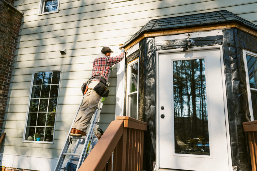 Construction workers repairing the siding of a house, window replacement Peoria IL, replacement windows Peoria IL, vinyl windows Peoria IL, energy efficient windows, window installation Peoria IL, replacement window contractor, residential window replacement, Vinyl Kraft windows, new windows for homes, home window replacement, window installers near me, affordable replacement windows, energy efficient replacement windows, Central Illinois window company, replacement window installation